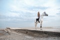 Elegant and beautiful confident young woman wearing stylish jockey outfit is holding reins and riding a white horse