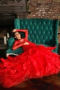 Elegant beautiful model sensual woman wearing stylish glamorous red dress for romantic date or party resting in decoration Royalty Free Stock Photo
