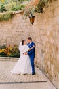 Elegant beautiful wedding couple, cheerful bride and loving groom near sandstone wall Royalty Free Stock Photo