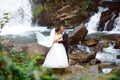 Elegant beautiful wedding couple posing near beautiful grand waterfall in mountain. luxurious wedding dress. Marriage couple outdo Royalty Free Stock Photo