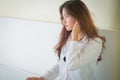 Elegant beautiful woman wearing white shirt posing in bedroom,