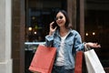 Elegant Asian female enjoys talking on the phone while walking at the shopping street Royalty Free Stock Photo