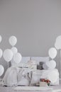 Elegant bedroom with king size bed with grey bedding, birthday cake and white balloons, real photo with copy space on empty wall Royalty Free Stock Photo