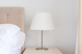 Elegant bedside lamp with white shade on night table in bedroom Royalty Free Stock Photo