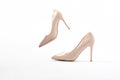 Elegant beige high heels. Beige patent leather shoes. One shoe floats in the air. The concept of lightness