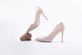 Elegant beige high heels. Beige patent leather shoes. One shoe floats in the air, resting on a stone. The concept of