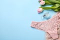 Elegant beige women\'s underwear, perfume and beautiful tulips on light blue background, flat lay. Space for text Royalty Free Stock Photo