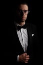 Elegant best man with glasses adjusting and buttoning black tuxedo Royalty Free Stock Photo