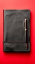 Elegant Black Leather Notebook and Pen on Vibrant Red Background for Business and Education Royalty Free Stock Photo