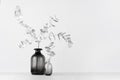 Elegant black and white home decor - black glass vase decorated silver leaves on light white wood table.