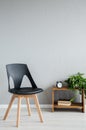 Elegant black wooden chair next to cabinet with clock and flowers in modern office interior