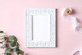 Elegant blank photo frame mockup, eucalyptus branch, ribbon on pink background. Flat lay, top view, copy space