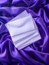 Elegant Blank White Book on Luxurious Purple Silk Fabric Background with Soft Folds and Shadows