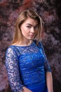 Elegant blonde woman in the blue evening sparkling dress is posing on marble colored background Royalty Free Stock Photo