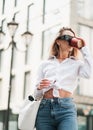 Elegant Blonde Woman Drinking Coffee While Walking Outdoors, Confident Female Entrepreneur Wearing Sunglasses and Golden Royalty Free Stock Photo