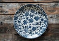 Elegant blue and white floral ceramic plate on a rustic wooden background Royalty Free Stock Photo
