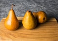 Elegant bosc or kaiser pears in yellow on a wooden plank and gray background