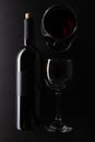 Elegant bottle and wineglasses of red wine on black background. Top view. Concept of advertising and promotion of alcoholic drinks Royalty Free Stock Photo