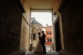 Elegant bride gently hugging groom in old courtyard in european