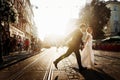 elegant bride and groom running and smiling in european city street at evening. luxury emotional wedding couple having fun. roman Royalty Free Stock Photo