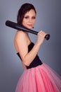 Elegant brunette girl with earrings in pink and black dress with a baseball bat Royalty Free Stock Photo