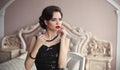 Elegant brunette with retro hairstyle posing in luxurious interior. Beauty fashion glamour girl portrait with red lips