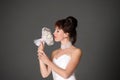 Brunette in a white wedding dress in the studio on a gray background with a wedding bouquet in her hands Royalty Free Stock Photo