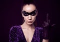 Elegant brunette woman in purple dress and sequins mask shows middle finger