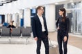 Elegant business couple standing with suitcase and airplane tickets at the waiting hall in the airport. Business travel Royalty Free Stock Photo