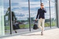 Elegant businessman call on mobile phone while walking with suitcase outside airport Royalty Free Stock Photo