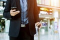 Elegant businessman checking e-mail on mobile phone while walking with suitcase inside airport Royalty Free Stock Photo