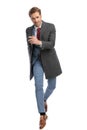 Elegant businessman with grey coat holding arm in fashion pose and jumping Royalty Free Stock Photo