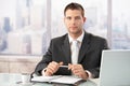 Elegant businessman sitting in bright office