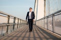 Elegant businessman walking on the bridge during sunset Royalty Free Stock Photo