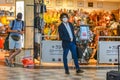 An elegant businessman wearing coronavirus protective mask walks in front of a made in italy leather shop at Pisa Airport, Italy