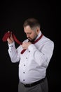 Elegant businessman in a white shirt, straightens ties his tie ob black background Royalty Free Stock Photo