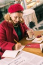 Elegant mature businesswoman making some notes sitting in bakery