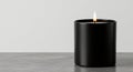Elegant candle in a black container, flame ablaze, set against a pristine white backdrop Royalty Free Stock Photo