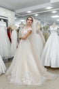 Elegant cheerful lady in bridal dress standing in wedding salon