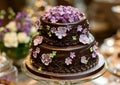 Elegant chocolate cake decorated with purple flowers on display