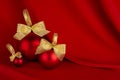 Elegant christmas background - traditional red christmas balls with gold shiny ribbon on scarlet smooth wavy silk, closeup. Royalty Free Stock Photo