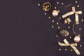 Elegant Christmas flat lay with golden tree ornament baubles, ribbons and fir cones on dark black background with copy space Royalty Free Stock Photo