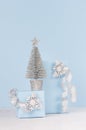 Elegant christmas gift boxes with shiny silver christmas tree on white wooden background and pastel blue wall. Royalty Free Stock Photo