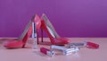 Elegant classic shoes close-up. Bright pink high heeled shoes. Luxury lipsticks near the pair of shoes. Pink and violet background
