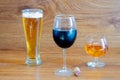 Composition of alcoholic drinks with glass of whiskey, glass of clear beer and glass of red wine on stage of oak tables with a Royalty Free Stock Photo