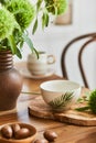 Elegant composition of classy dining room interior design with rustic table, beautiful porcelain, flowers and kitchen accessories. Royalty Free Stock Photo