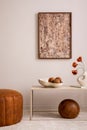Elegant composition of living room interior with mock up poster frame, broen pouf, stylish bowl with coconut, vase with dried