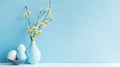 Elegant composition with vase with fresh spring branches with flowers and a bowl with eggs on light blue background.Created with