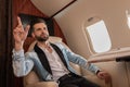 Elegant, confident man showing come gesture while calling for air steward Royalty Free Stock Photo