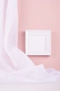 Elegant contemporary gallery in simple style with black square photo frame hanging on soft light pastel pink wall with white silk. Royalty Free Stock Photo